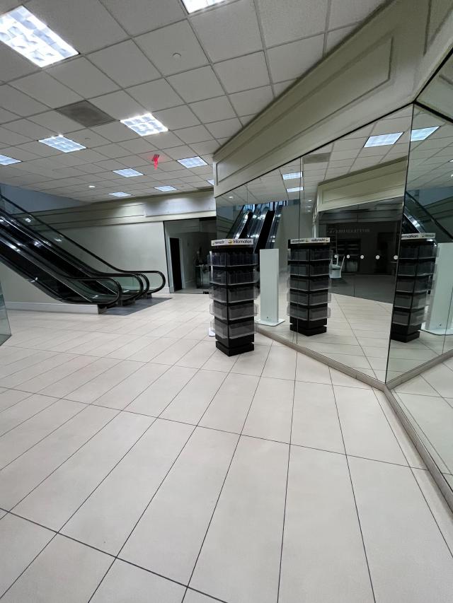 Fluorescent lit atrium with an escalator and an empty card rack