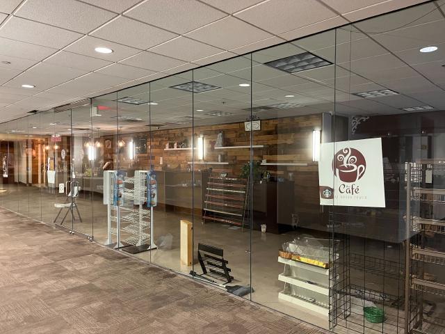 A messy closed down cafe, branding still in place, visible through a glass wall. An out of place chair inside.