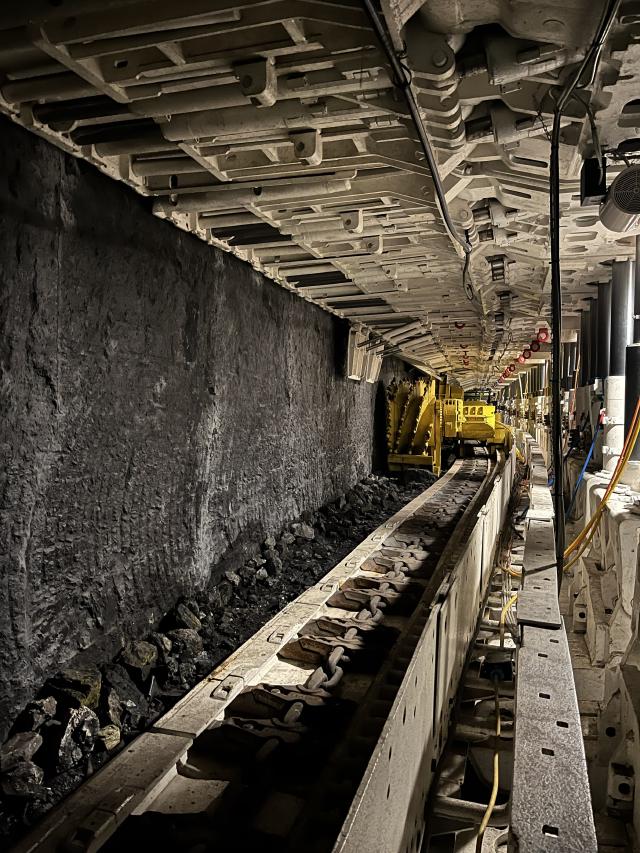A large yellow cutting machine cutting away at a coal face