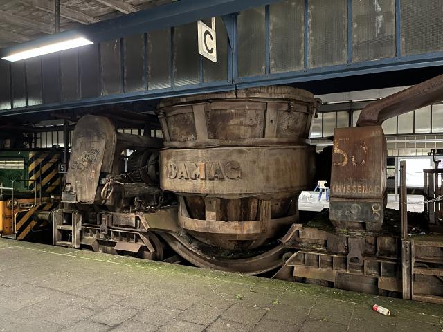 A train carriage with a large smelting pot in a platform at a station.